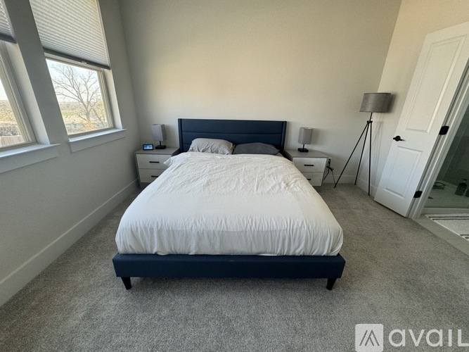 A bedroom with a large bed and two lamps.