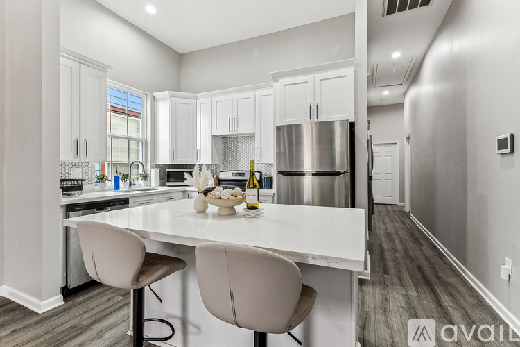 A modern kitchen with a white island and bar stools.