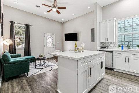 A modern kitchen with white cabinets and a green chair.