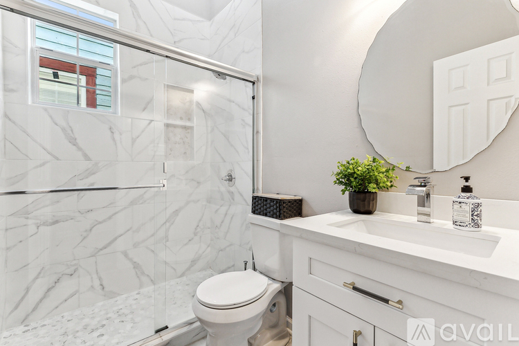A bathroom with a marble patterned shower and a white toilet.