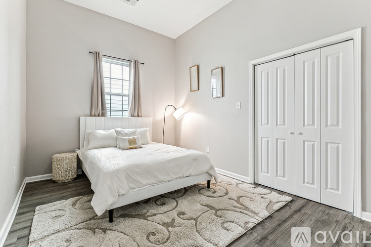 A bedroom with a white bed and a white rug.