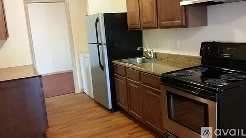 A kitchen with a black fridge, black stove, and wooden cabinets.