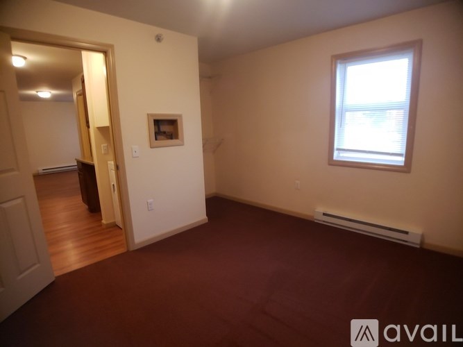 A room with a window and a brown carpet.