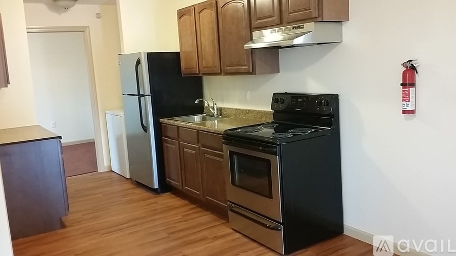 A kitchen with black appliances and wooden cabinets.