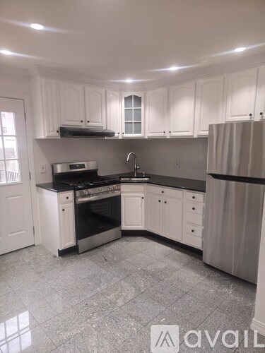 A kitchen with white cabinets and a black countertop.