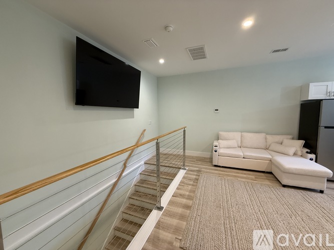 A living room with a staircase and a flat screen TV mounted on the wall.
