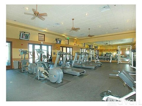A gym with a variety of equipment including treadmills, weights, and a fan.