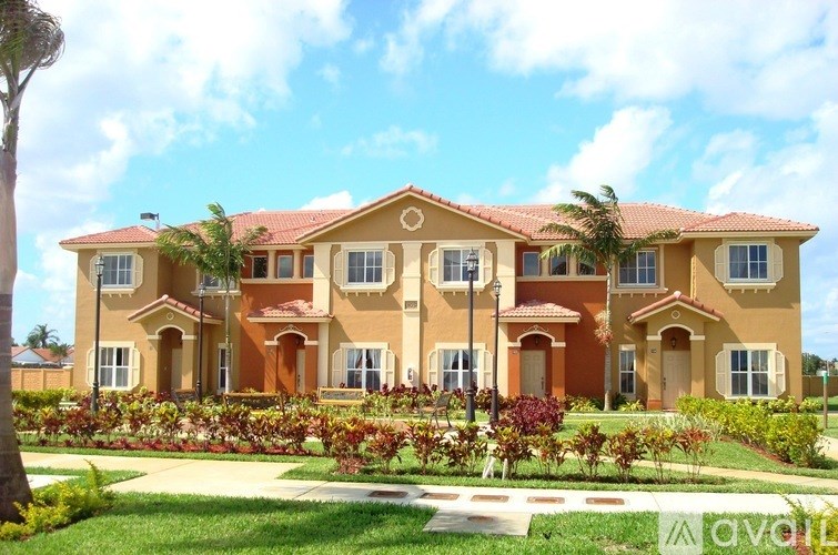 A large, multi-story house with a red tile roof and a well-manicured lawn in front.
