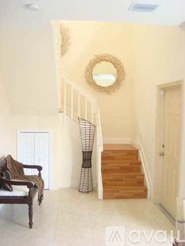 A staircase with a wreath on the wall and a chair in the foreground.
