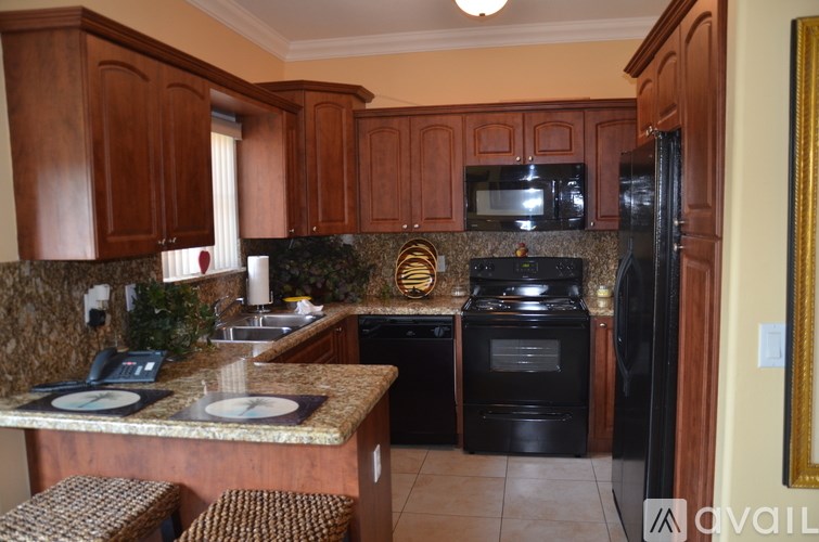 A kitchen with brown cabinets and black appliances.