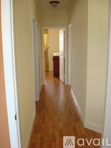 A hallway with wooden floors and white walls.