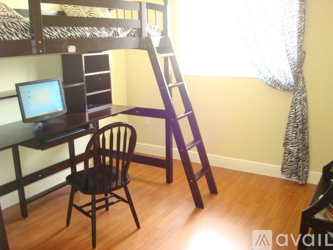 A room with a bunk bed, a desk with a computer, and a ladder.