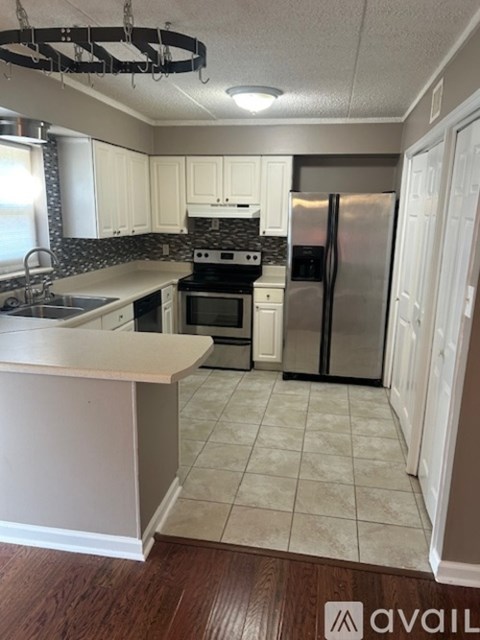 A kitchen with white cabinets and a black refrigerator.
