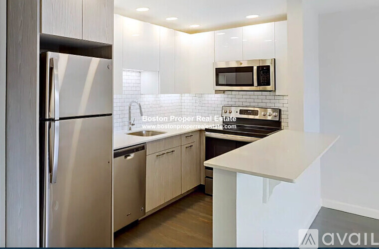 A modern kitchen with a stainless steel refrigerator and white countertops.