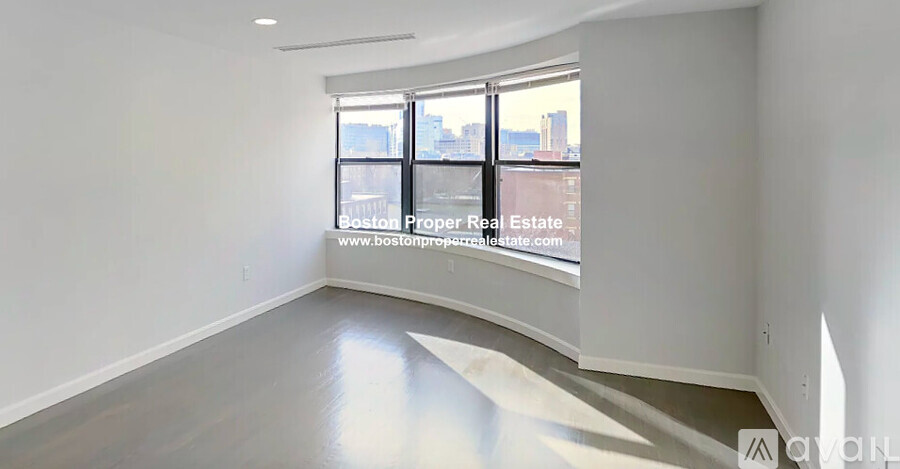A spacious empty room with a view of the city through the windows.