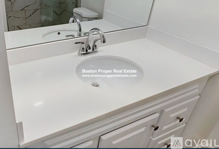 A white bathroom sink with a chrome faucet and a mirror above it.