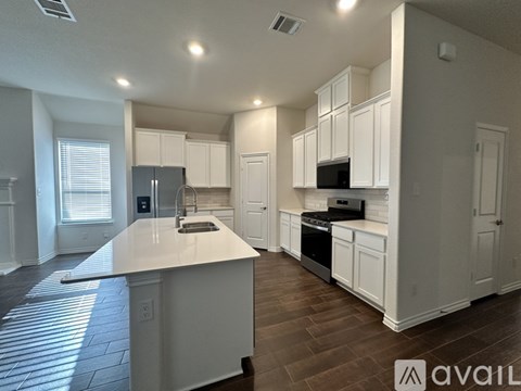 A kitchen with white cabinets and a wooden floor.