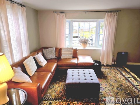 A living room with a brown leather couch and a floral rug.