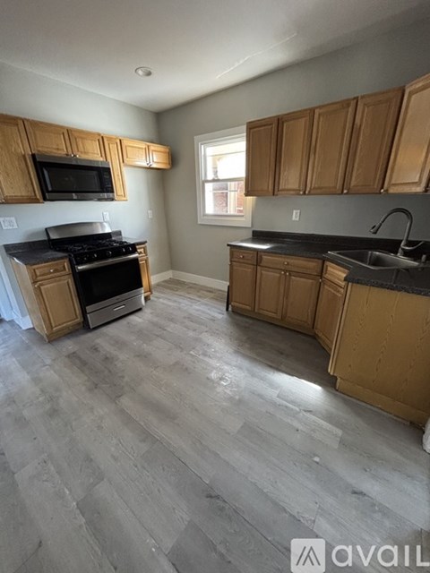 A kitchen with wooden cabinets and a grey floor.