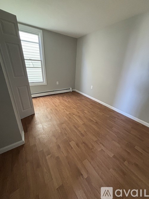 A room with wooden flooring and a window with blinds.
