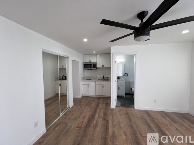A spacious room with a ceiling fan and wooden flooring.