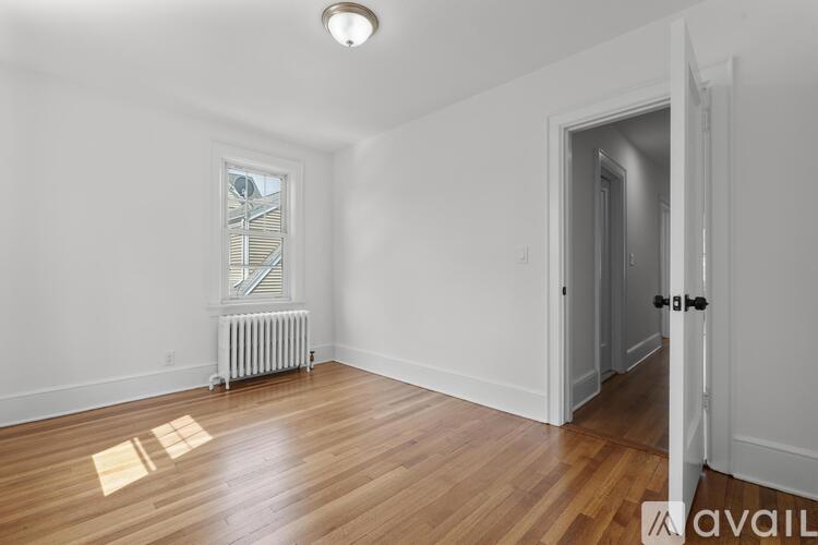 A room with wooden floors and a window with a view of trees and a building outside.