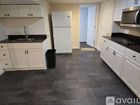 A kitchen with white cabinets and a black countertop.