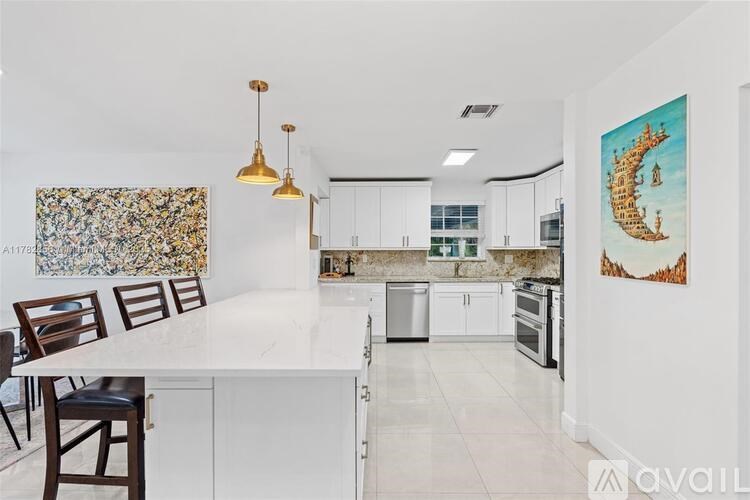 A kitchen with white cabinets and a marble island.