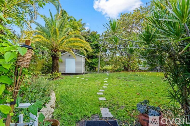 A garden with a stone pathway leading to a shed.