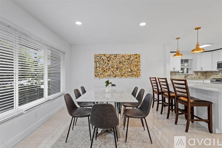 A dining room with a table set for six and a kitchen area in the background.