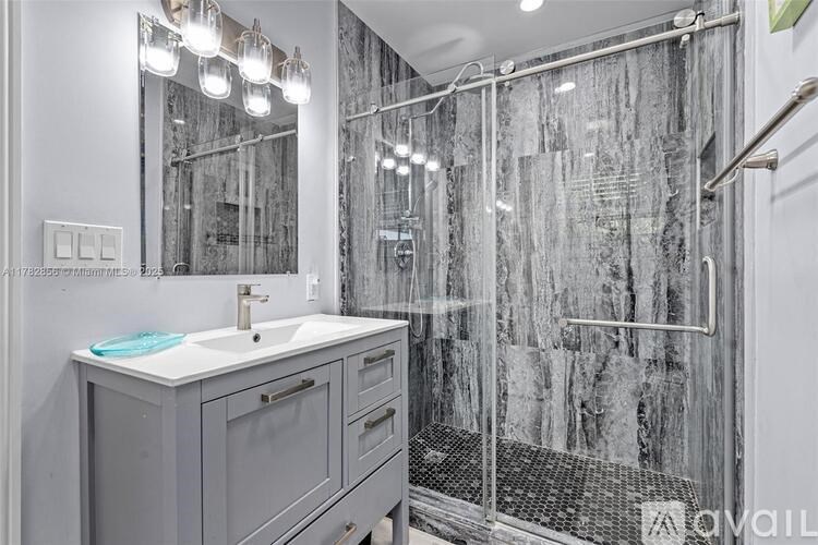 A bathroom with a sink, mirror, and shower.