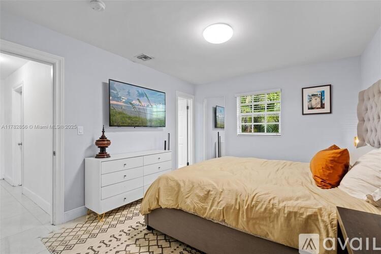 A bedroom with a bed, dresser, and television.