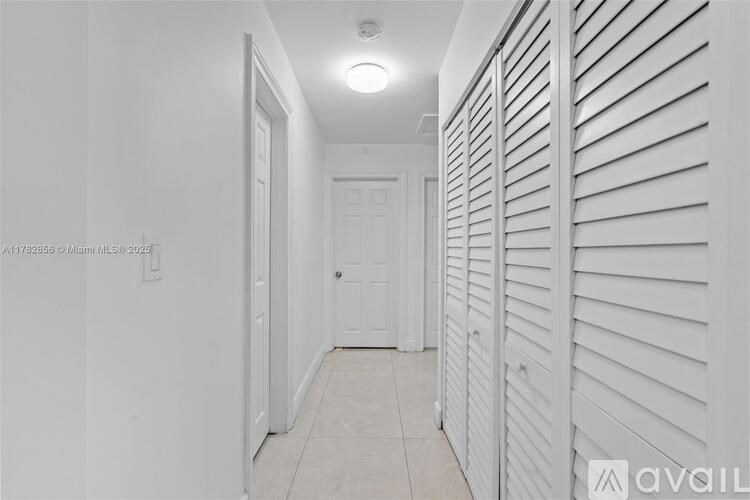 A hallway with white walls and a tiled floor.