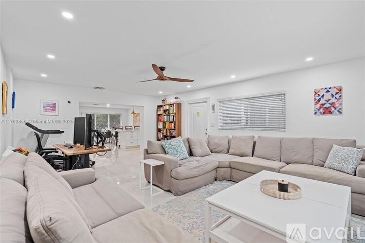 A spacious living room with a grey sofa set, a white coffee table, and a ceiling fan.