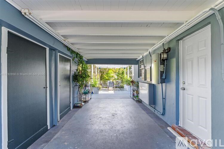 A long, narrow alleyway with a white door on the right and a metal gate on the left.