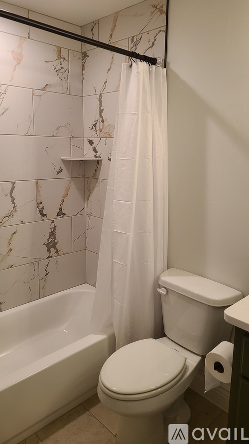 A bathroom with a marble wall and a white toilet.