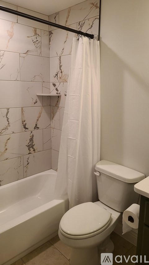 A bathroom with a marble wall and a white toilet.