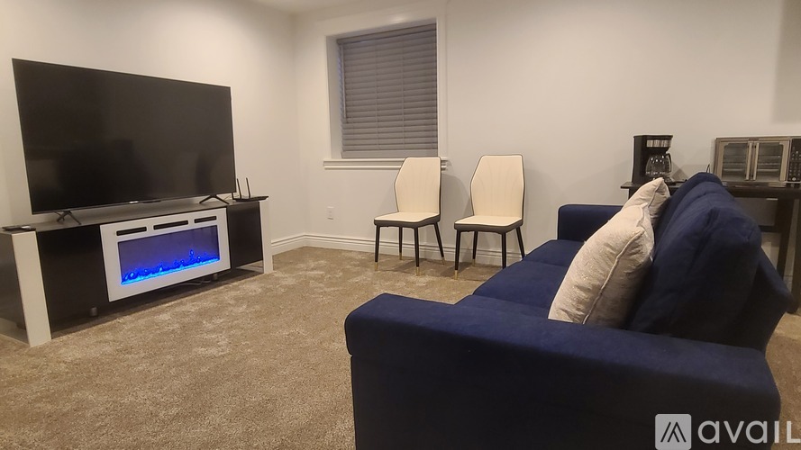 A living room with a television, two chairs, and a sofa.