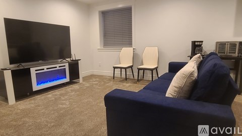 A living room with a television, two chairs, and a sofa.