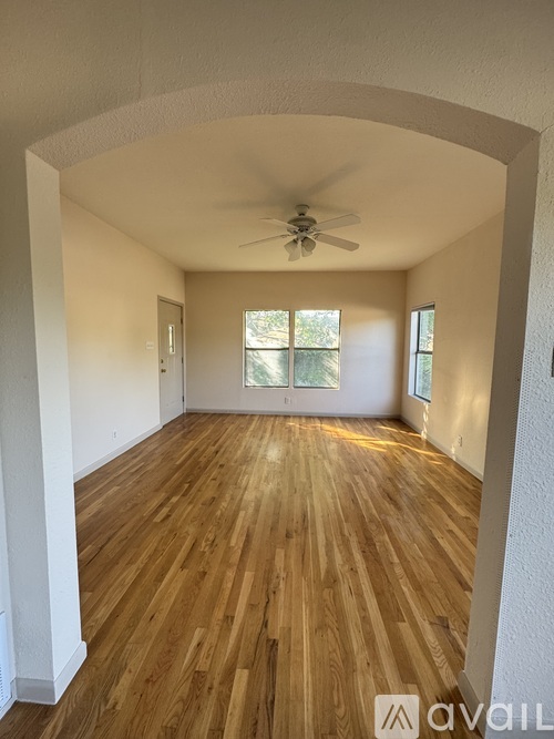 A spacious room with wooden floors and a ceiling fan.