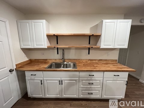 A kitchen with white cabinets and a wooden countertop.