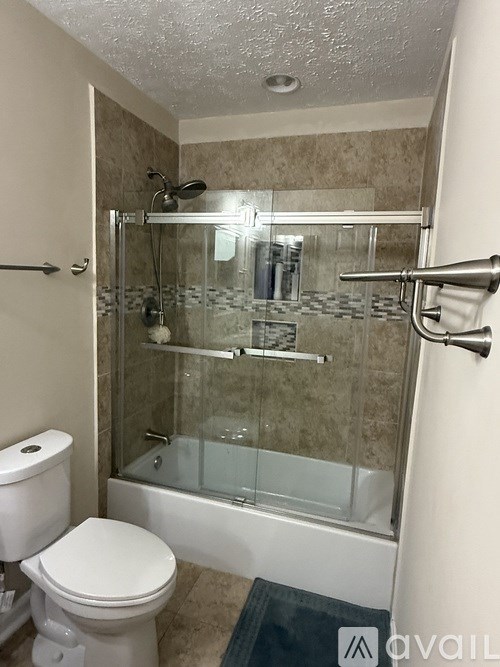 A bathroom with a toilet, a glass shower stall, and a glass door.