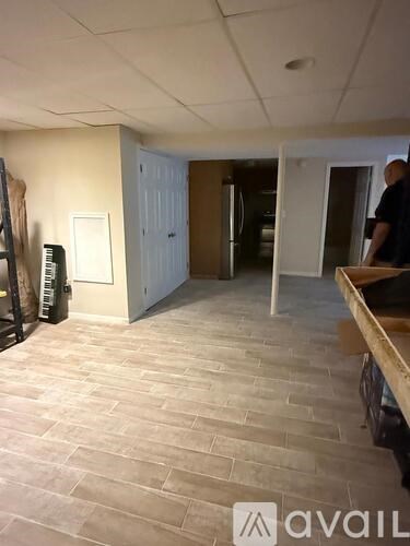 A man is standing in a room with a wooden bench and a piano.