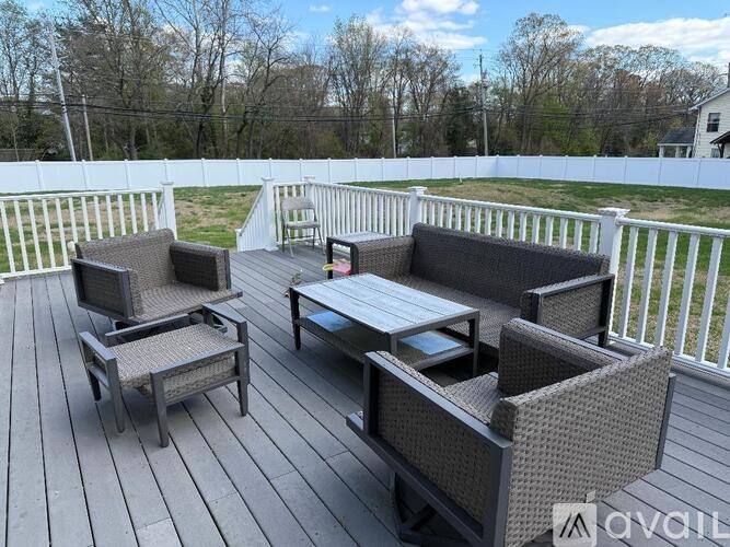 A patio with a white fence and grey furniture.