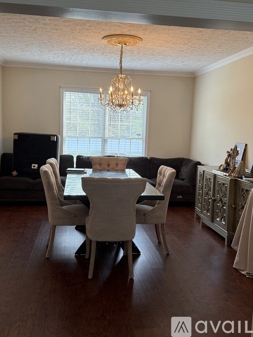 A dining room with a chandelier, a table with chairs, and a television.