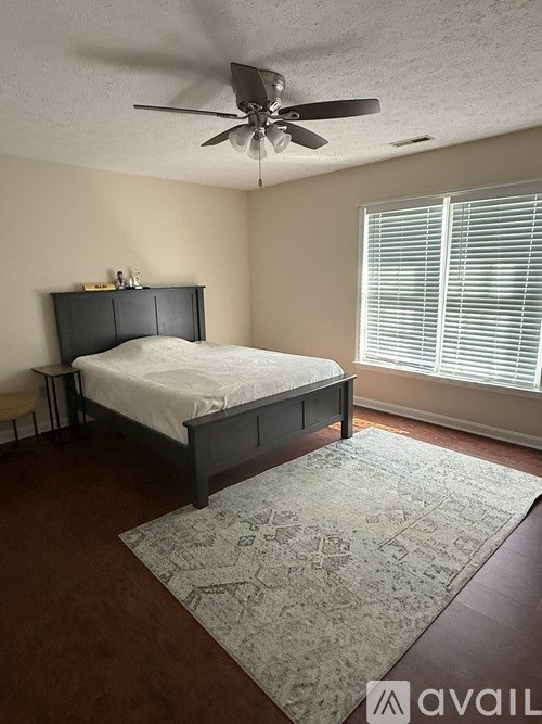 A bedroom with a bed, a rug, and a ceiling fan.