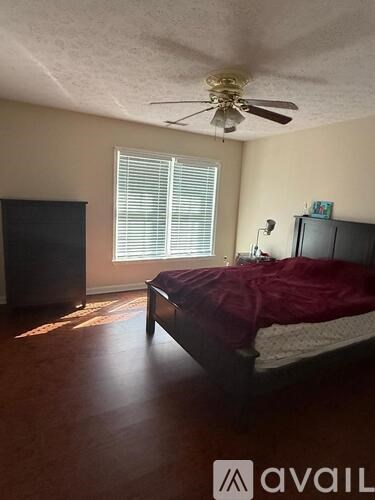 A bedroom with a bed, a ceiling fan, and a television.