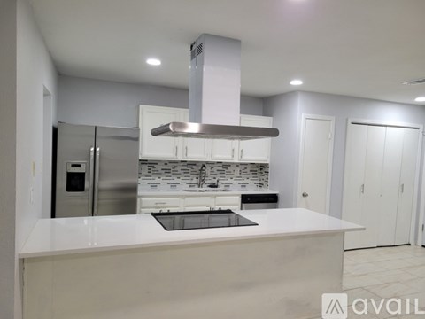 A modern kitchen with a stainless steel refrigerator and a white countertop.