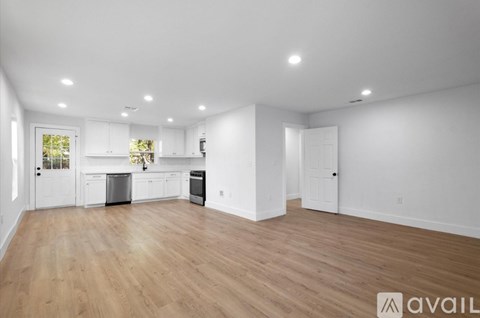 A spacious kitchen with white cabinets and a wooden floor.