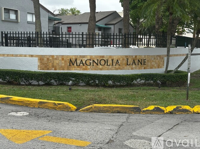Magnolia Lane is written on a wall next to a sidewalk.